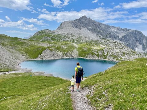 Father and son hiking to beautiful lake Butzen, Butzensee, in Arlberg region close to Lech. Vorarlberg, Austria.