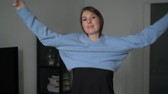Young woman put on blue casual pullover sweater. Girl in dressing room, try on.