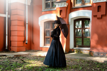 Mysterious beautiful lady dressed in strict black clothes of the 19th century looks suspiciously...