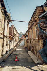 Old collapsing buildings with wooden supports and warning road sign in Tbilisi, Georgia.