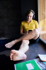 Naklejka premium A 14-year-old guy with problematic skin listens to music with headphones