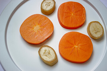 White dish with sliced juicy persimmon slices close-up