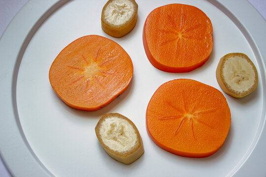 White dish with sliced juicy persimmon slices close-up