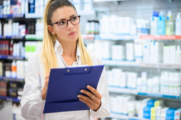 Female pharmacist checking wares in her store