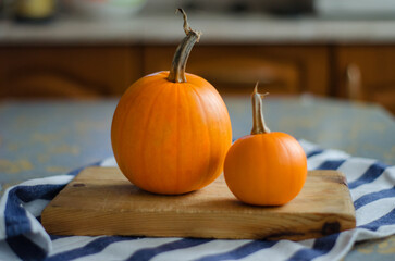 orange pumpkins lie on a wooden chopping board on the kitchen table, pumpkin pie, halloween