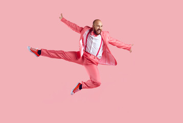 Happy confident young bald man jumping in the studio. Full body shot of a funny joyful male dancer...