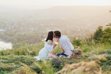 Attractive couple enjoying romantic picnic in the countryside and kissing. 