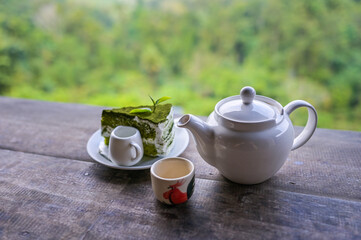 Tea set, Cups and teapot of green tea on wooden board with mountain and forest background