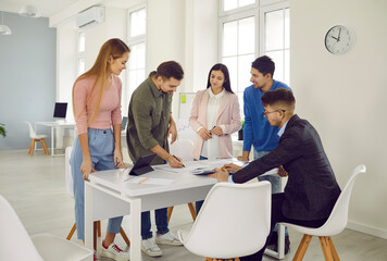 Diverse young businesspeople brainstorm cooperate at desk in office discuss ideas together. Employee or colleague collaborate involved in team meeting at workplace. Teamwork concept.