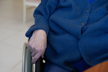 gros plan sur la main d'une personne âgée assise dans un fauteuil roulant