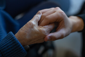 gros plan sur la main d'une personne âgée tenant celle d'un jeune homme. Symbole de la compassion et de la solidarité - obrazy, fototapety, plakaty