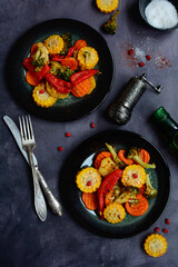 vertical composition. Baked vegetables on plates on a dark background. Healthy food concept. View from above