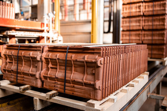 Factory products ready for packaging. Factory production of roof tiles and construction materials. Automated industrial machine transporting packs of quality roof tiles for building industry.