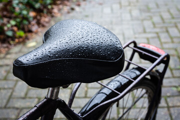 Close up of wet saddle of a bicycle,    bike in the rain with water drops on the saddle, selective...