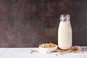 Soy milk in a vintage bottle with ingredients. Vegan, plant based, non dairy milk. Side view...