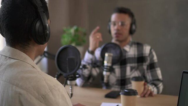 Man at podcast chat with colleague, defocused host wear headphone Spbd. Dj speaker talk to guest in studio. Concept radio, broadcast, record. Announcer stream on air