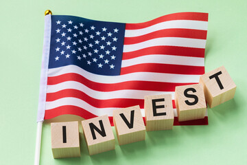 Wooden cubes with text and a flag on a colored background, the concept of investment from America