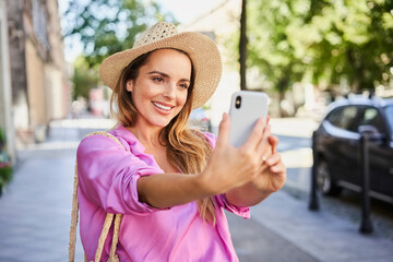 Stylish woman taking selfie while walking on street