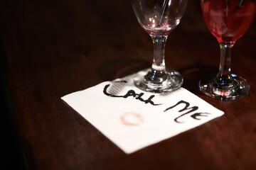Get the message. Closeup of a flirtatious message written on a napkin on a bar counter. - obrazy, fototapety, plakaty