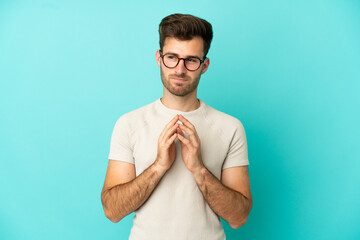 Young caucasian handsome man isolated on blue background scheming something