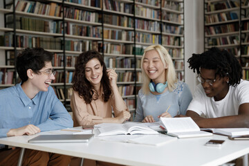 Happy relaxed friendly diverse millennial students communicating, preparing together for exams in...