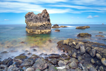 Long exposure shot of volcanic shore with big rocks in the Ocean. Rough Coast of El Hierro. Recreation on the Canary Islands. Smooth water surface.