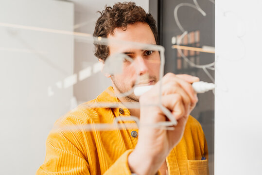 creative caucasian man draws on a glass board his strategies for the success of his company. brainstorming. Person working in the office.