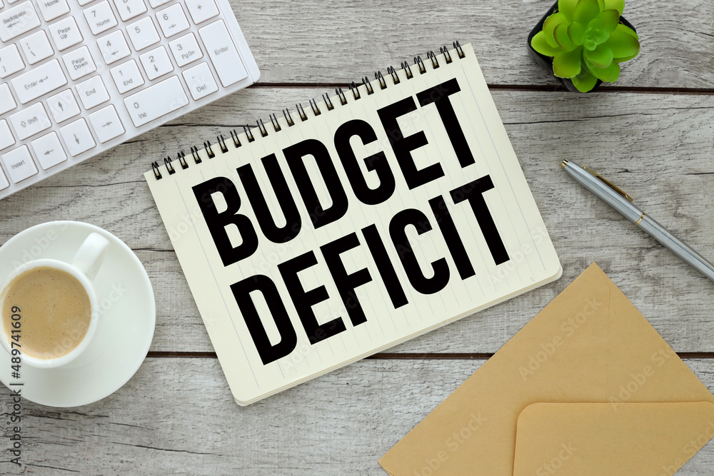 Poster budget deficit. notepad with text on a wooden table and a cup of coffee. plant keyboard envelope. wo