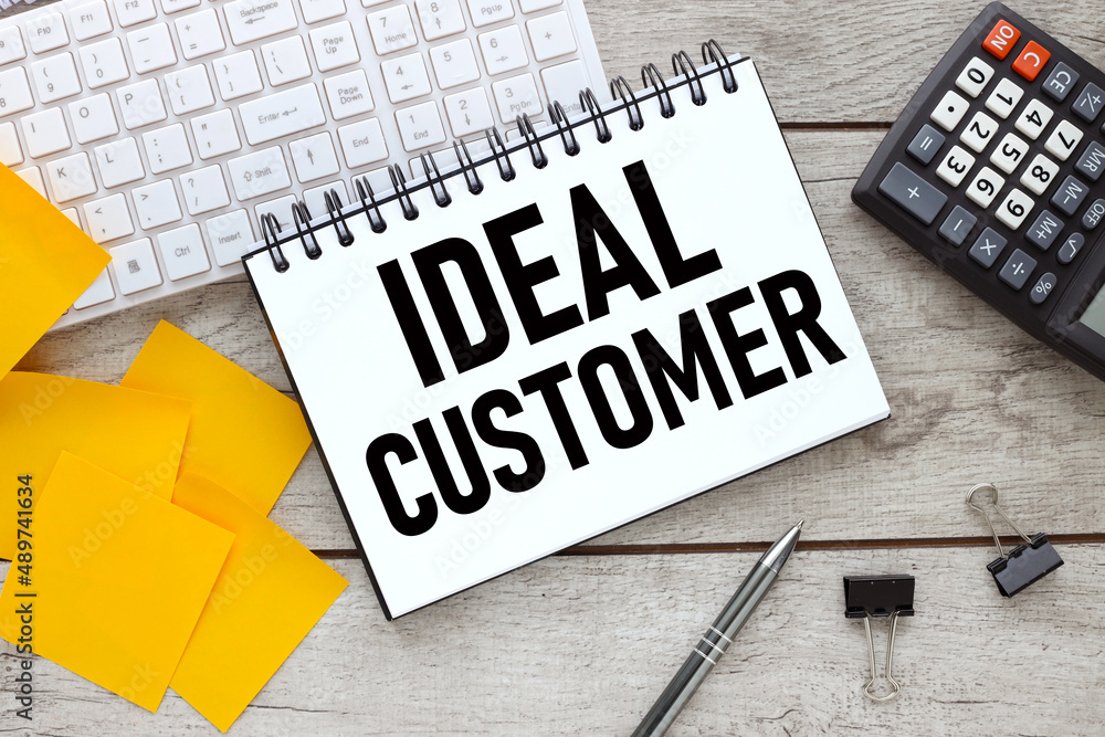 Aufkleber ideal customer. notepad with text on a wooden table and yellow stickers. keyboard . working table