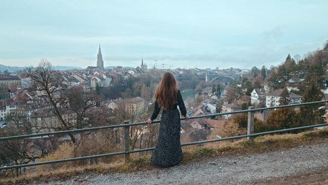 A beautiful girl looking from above at the old town of Bern over the river. A woman exploring Bern the capital of Switzerland with Swiss medieval architecture.