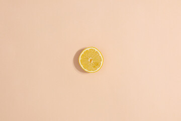 One sliced lemon on pastel beige background. Minimal flat lay summer fruits