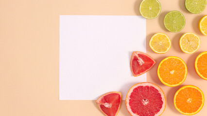 Fototapeta na wymiar Creative paper card copy space with citrus fruits arrangement on pastel beige background. Flat lay