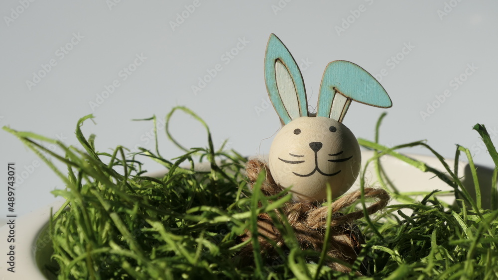 Wall mural cheerful smiling easter bunny sticking out its head from green grass easter nest isolated