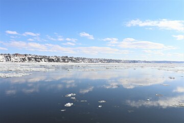 River landscape in winter. Iceberg on a river. St-Laurent river in Quebec city during the winter. Blue sky and water.  Reflection of the water.