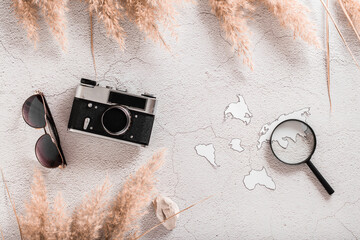 Flat lay concept travel. Vintage camera, sunglasses, continent templates and magnifier on textured...