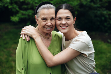 Grandmother and granddaughter hugging and smiling in the garden