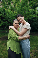 Fototapeta premium Grandmother and granddaughter hugging and smiling in the garden
