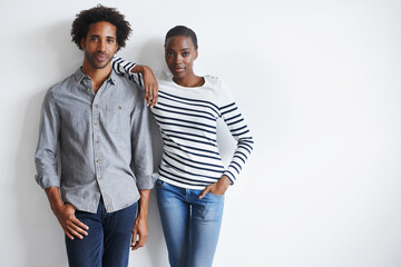 Simple and stylish. A portrait of a stylish young couple standing together affectionately against a white wall.