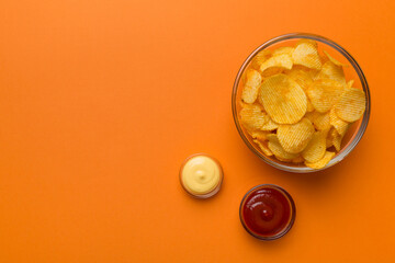 Top view chips with sause in bowl on colored background, top view with copy space