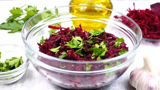 A salad of grated beets in a salad bowl are sprinkled with the chopped parsley leaves