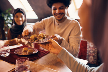 Close-up of Islamic people eat baklava at dining table at home.