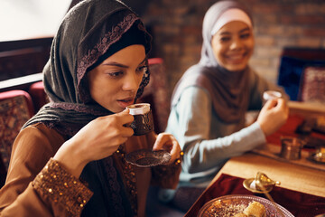 Young Middle Eastern woman drinks Turkish coffee during dessert at home.