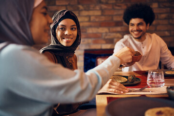 Young happy Muslim woman and her family enjoying in Iftar meal at home.