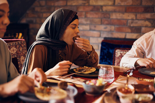 Young Muslim woman enjoys while eating falafel while eating with family at home.