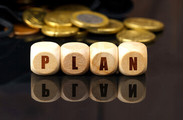 On a black surface are coins and cubes with the inscription - PLAN