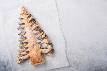 Puff pastry Christmas tree with chocolate paste, sprinkled with powdered sugar on a gray background. Christmas or Xmas pastries. Top view. Copy Space