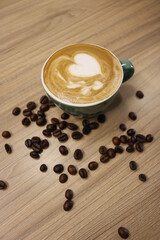green cup of coffee and beans on wooden table