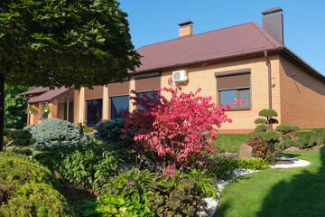 Backyard garden with nicely trimmed bonsai, bushes and stones in front of the European style villa. Landscape design. High quality photo