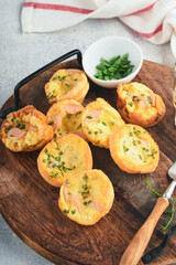 Delicious egg muffins with green onions, bacon, cheese and tomatoes on wooden board on light background. Healthy high protein and low carb breakfast. Homemade food.
