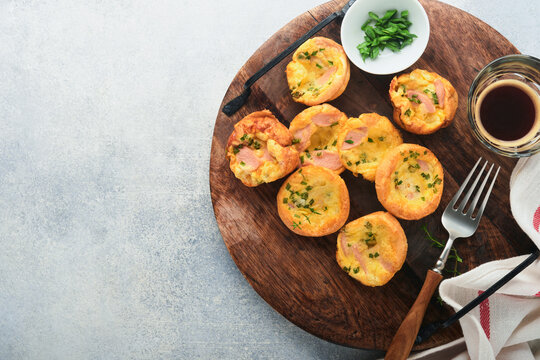 Delicious egg muffins with green onions, bacon, cheese and tomatoes on wooden board on light background. Healthy high protein and low carb breakfast. Homemade food.